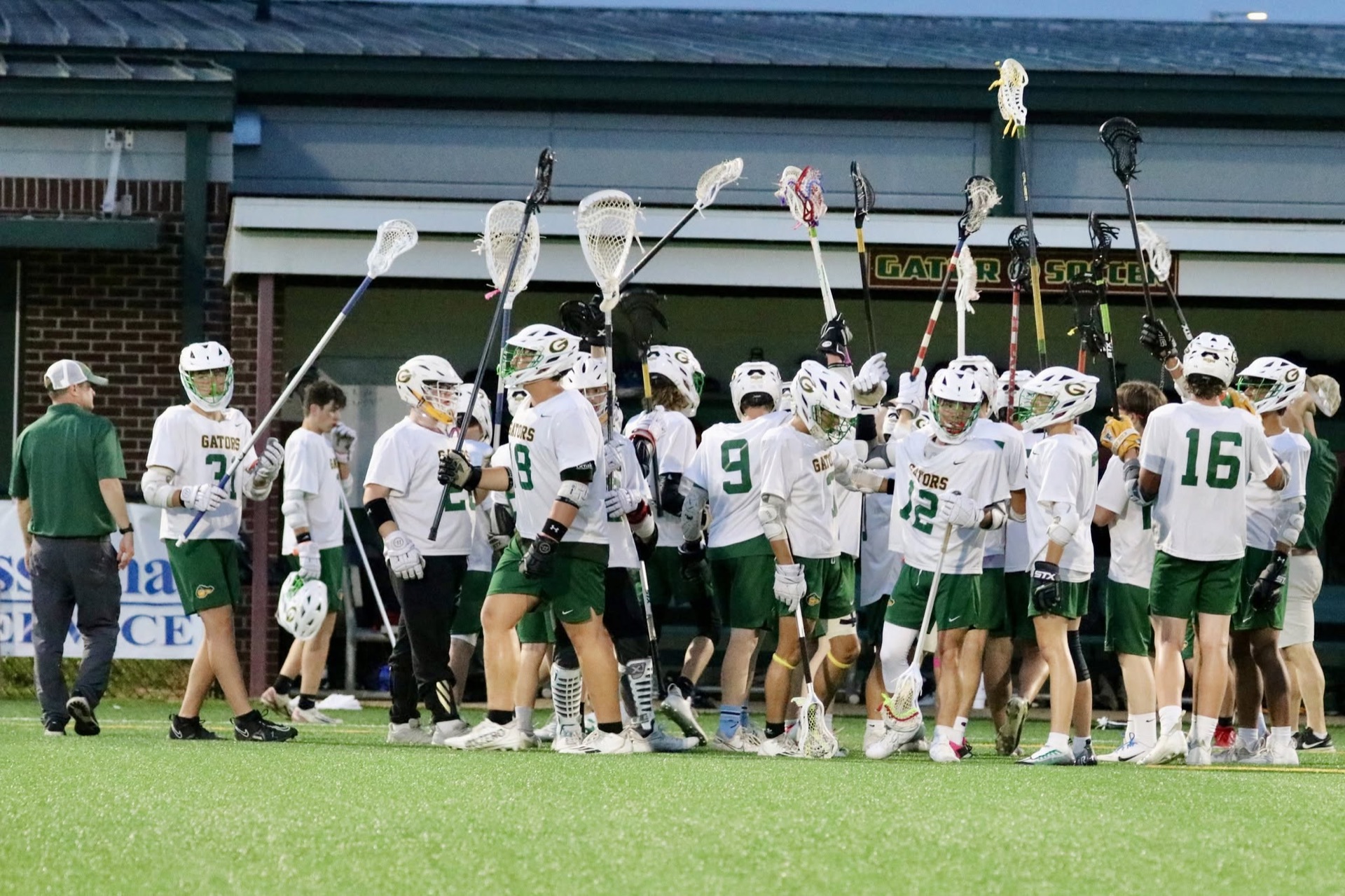 Greenwood Gators lacrosse players raising their sticks on the field